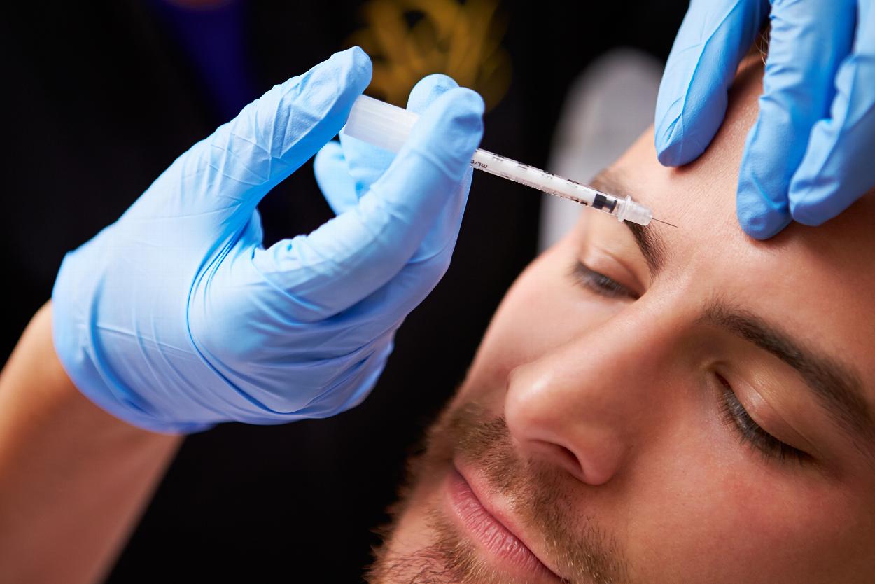 Doctor applying dermal filler to man's brow