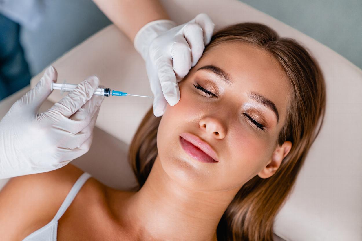Woman having cheek dermal filler applied by doctor
