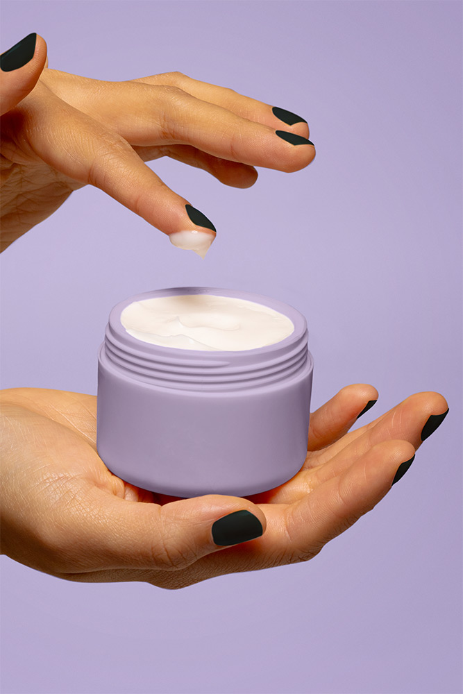 Closeup of hands holding tub of skincare cream